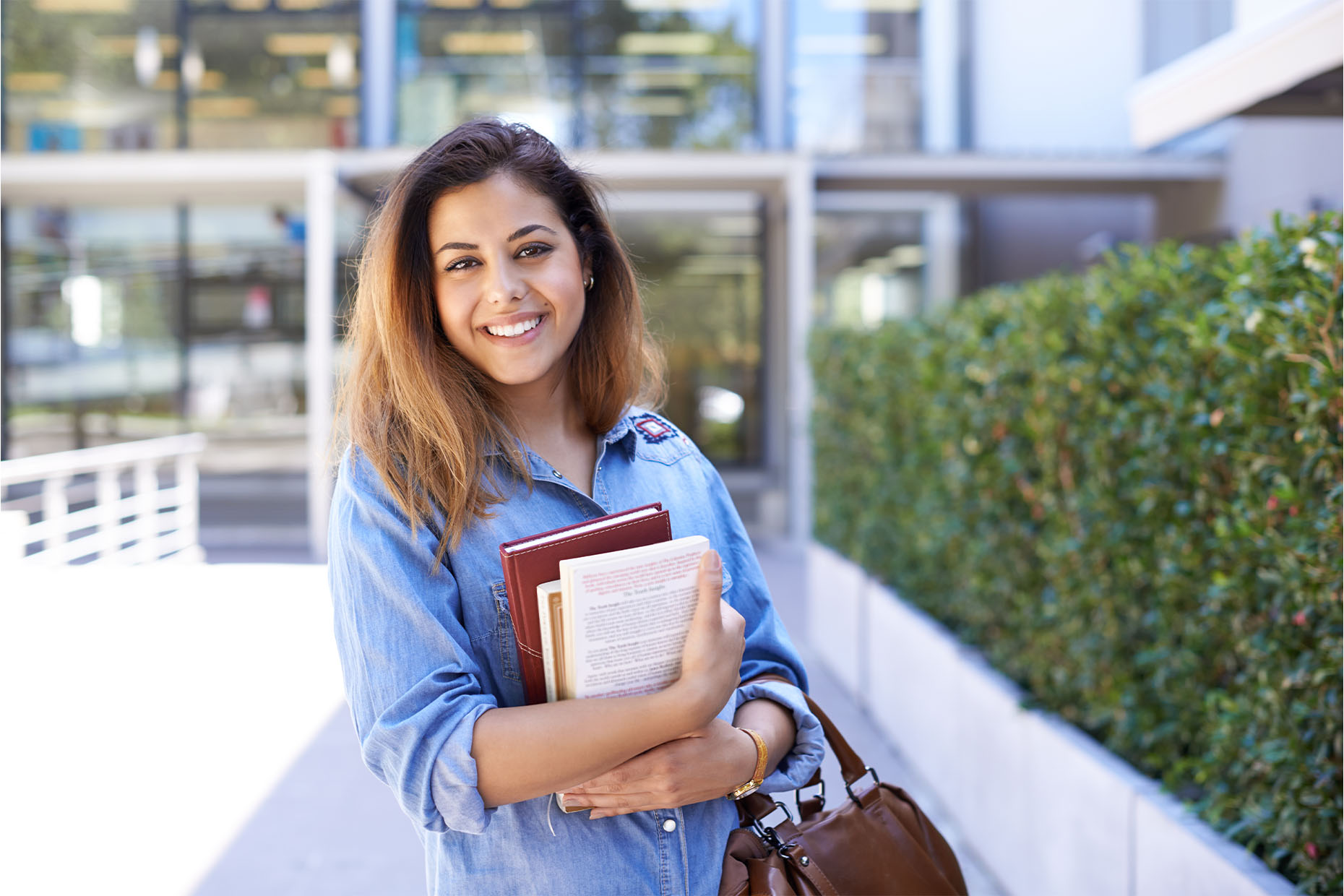 female holding books on college campus