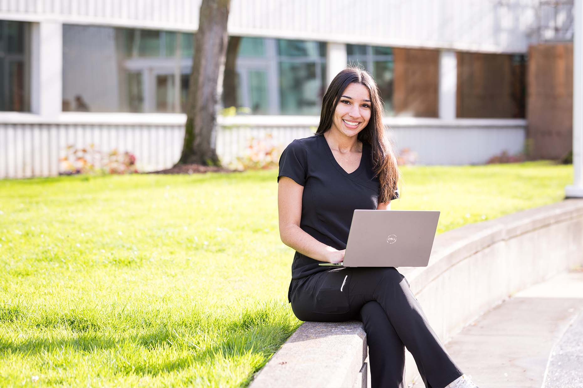 female student using laptop on lawn