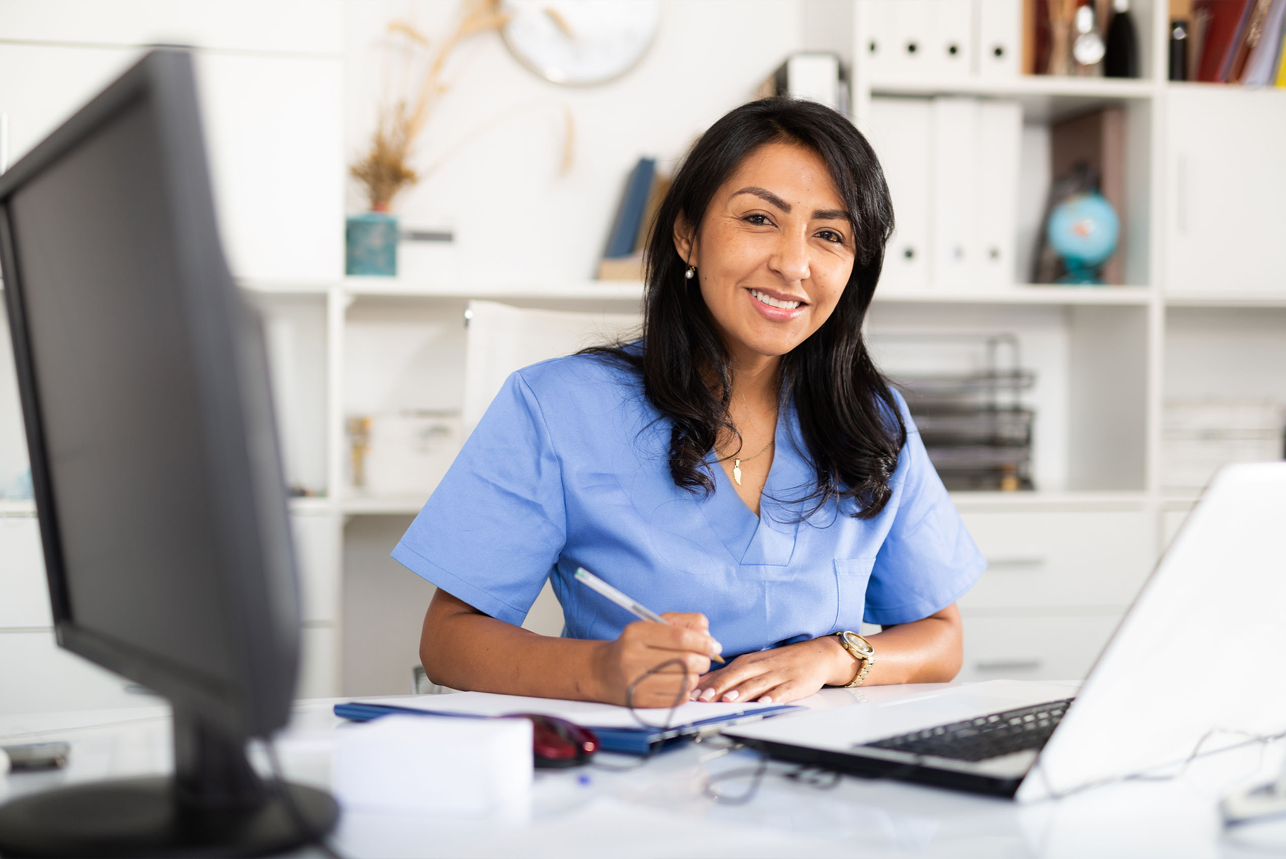 nurse looking at the camer while writing on medical pad