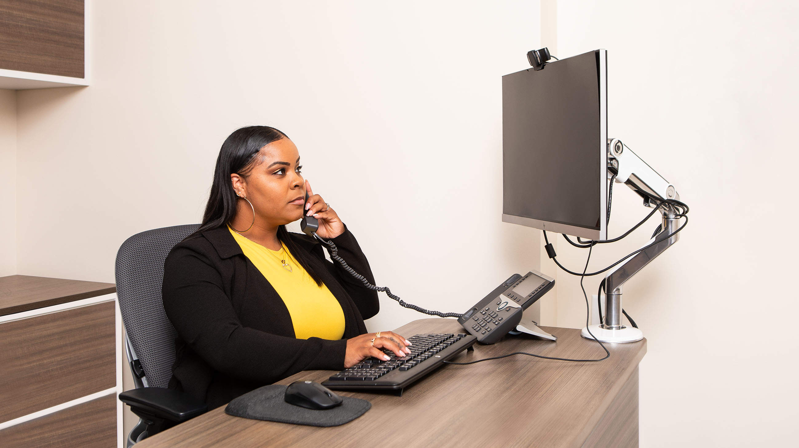 professional woman taking call while in front of computer