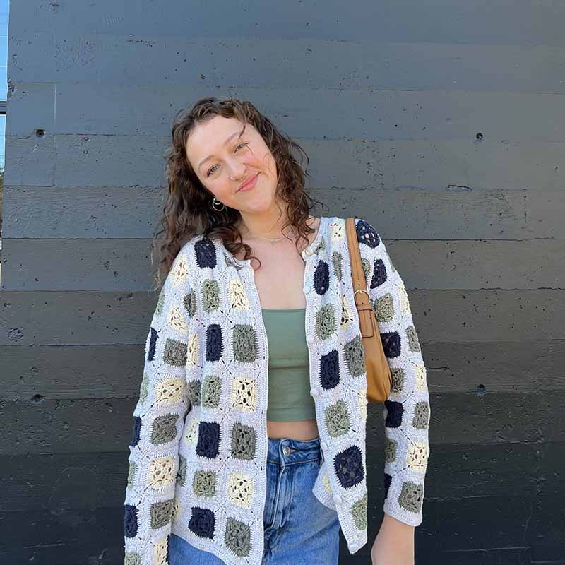 young woman smiling outside in cardigan